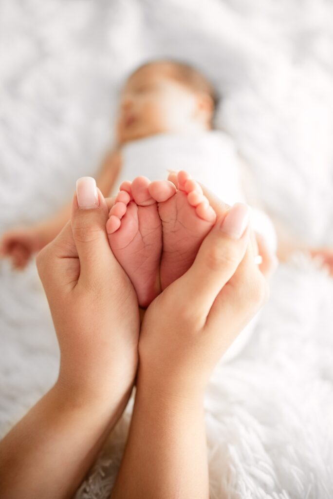 Close-up of parent gently holding a newborn baby's feet, symbolizing love and care.